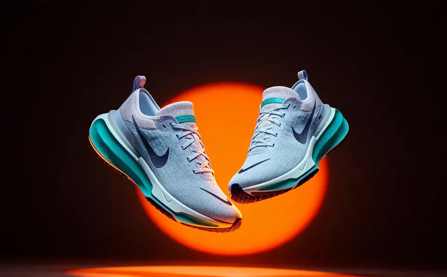 A pair of running shoes floating in front of an orange sun