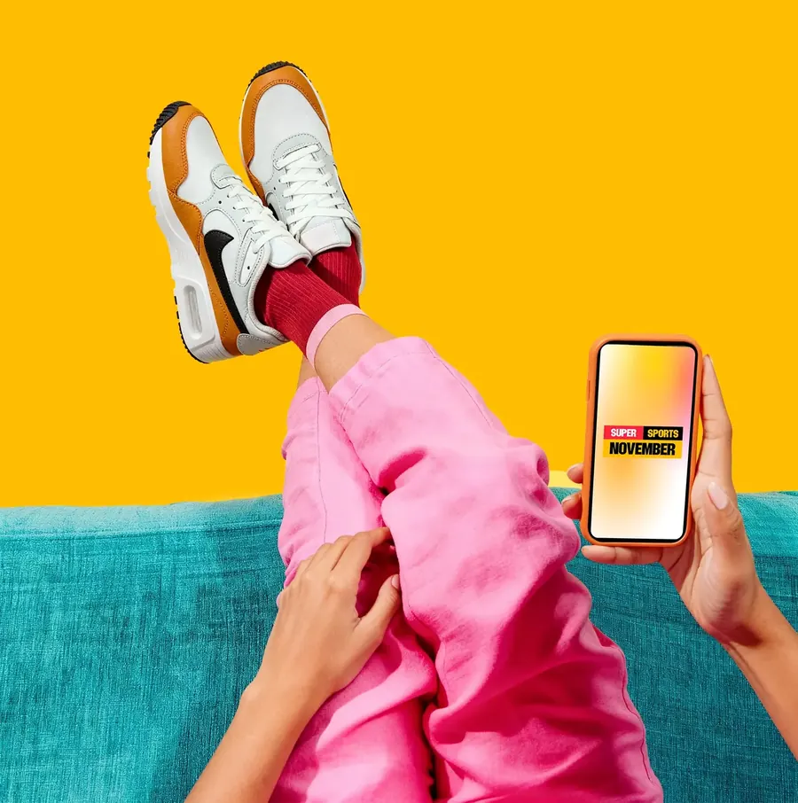 Crossed legs in sneakers with a phone showing the sale