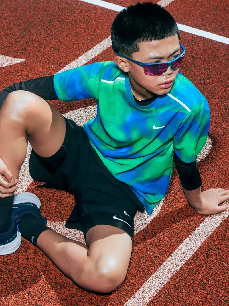 A boy in a Nike tee sitting on the track