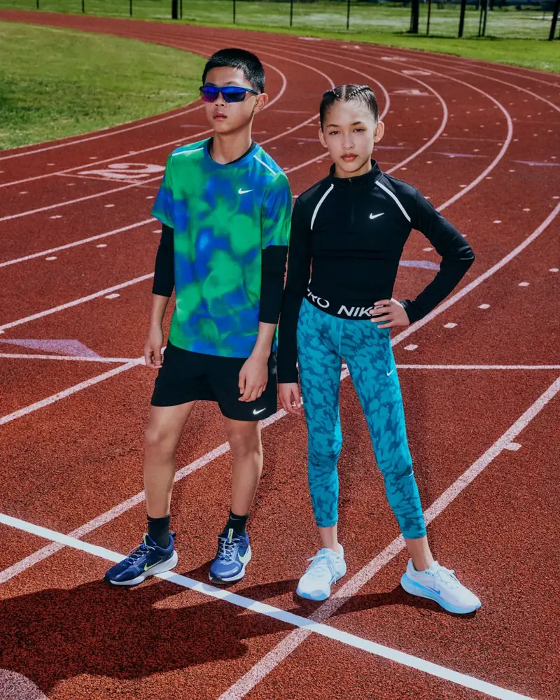 Two kids in Nike kit standing on a running track