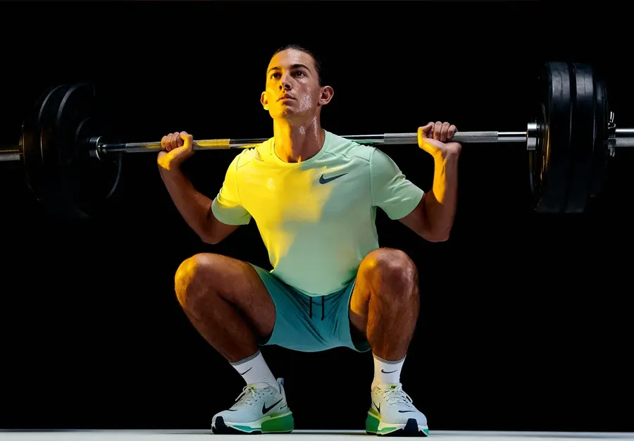 An athlete squatting a barbell on a black stage